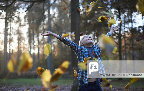 Junge wirft Blätter in die Luft