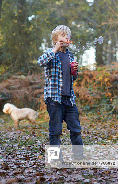 Boy blowing bubbles in forest