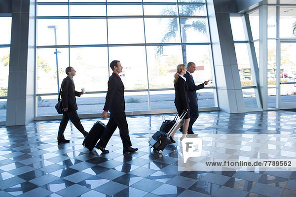Businesspeople walking through airport with suitcases