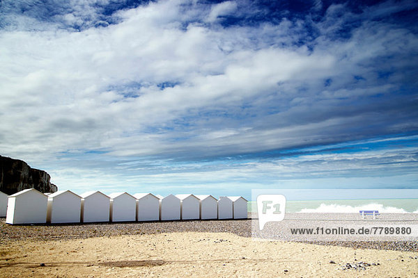 Weiße Strandhütten in einer Reihe am Kiesstrand