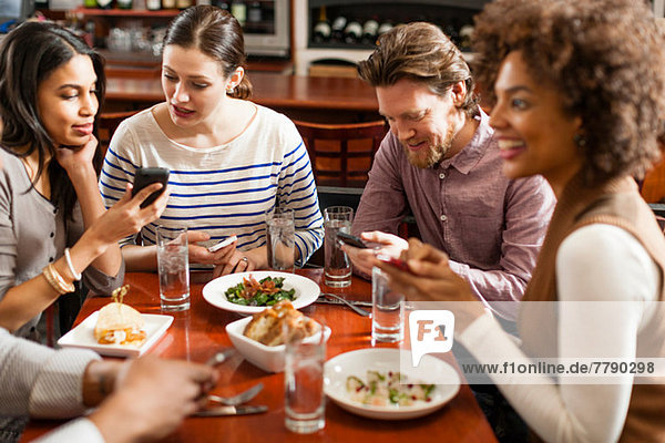 Freunde im Restaurant texten und Fotos mit dem Handy zeigen