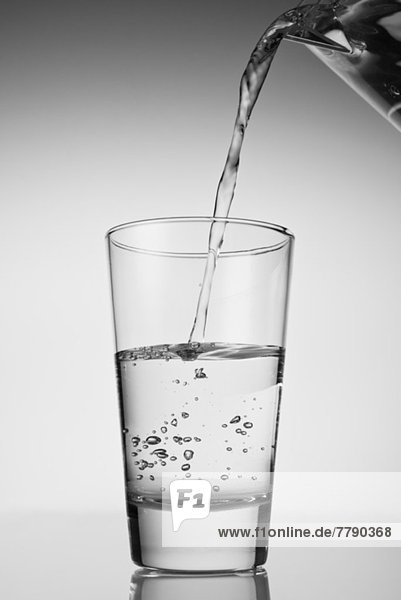 Wasser wird in Trinkglas gegossen