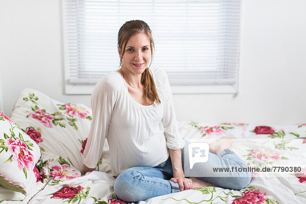 Porträt einer schwangeren Frau auf dem Bett