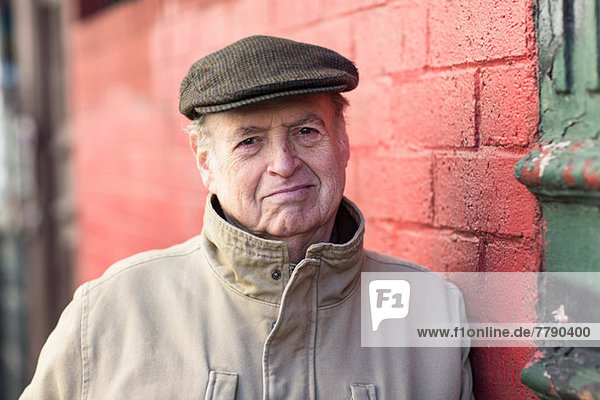 Portrait of senior man leaning on red brick wall