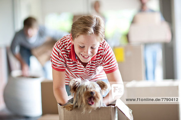 Boy moving house with dog in box