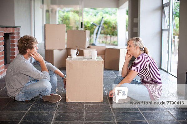 Young couple moving house sitting on floor with box