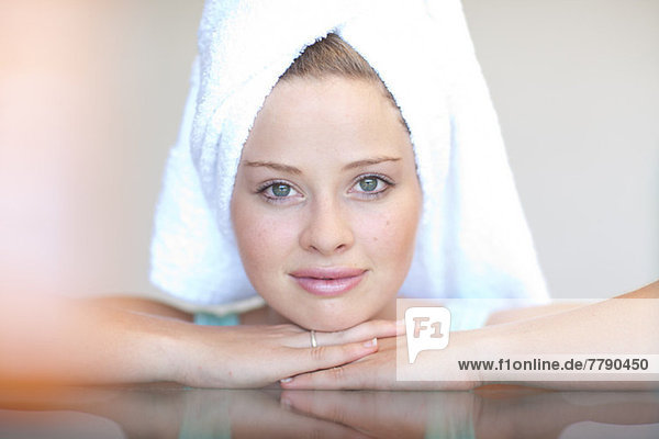Young woman wearing towel on head with chin on hands