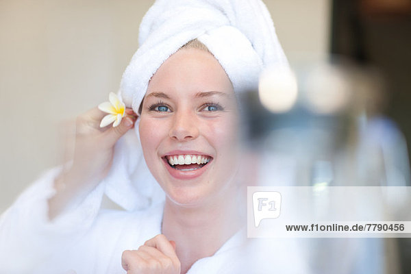 Young woman with towel on head and flower behind ear