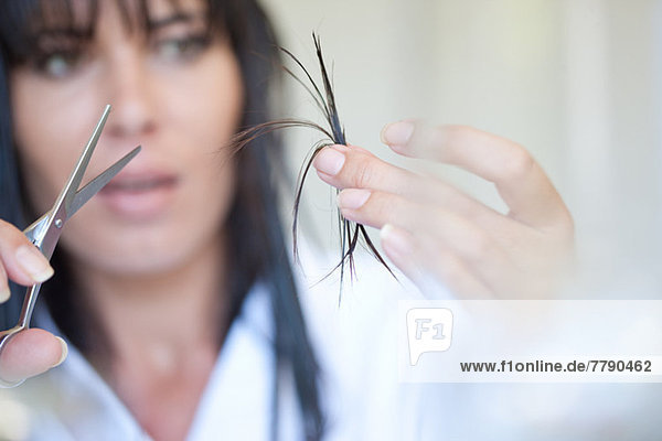 Mid adult woman holding scissors and hair
