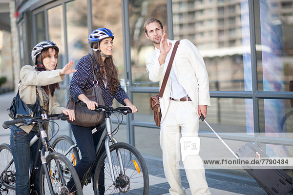 Young women with bicycles asking young man for directions