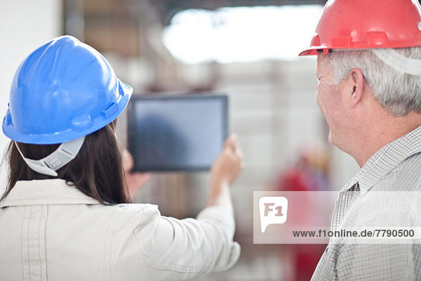 Rückansicht der Mitarbeiter beim Betrachten des digitalen Tabletts auf der Baustelle