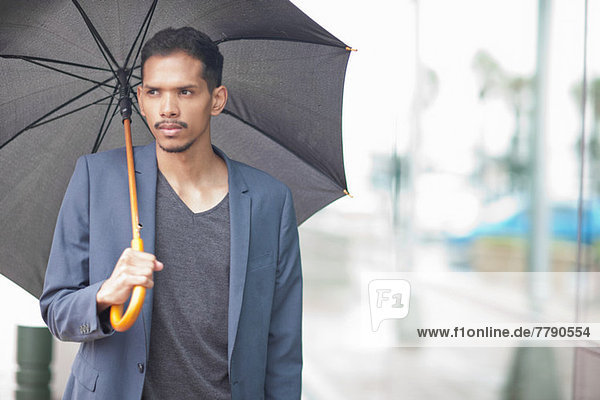 Junger Mann mit Regenschirm
