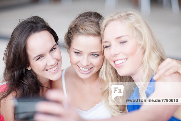 Three young women taking photos and showing them to each other