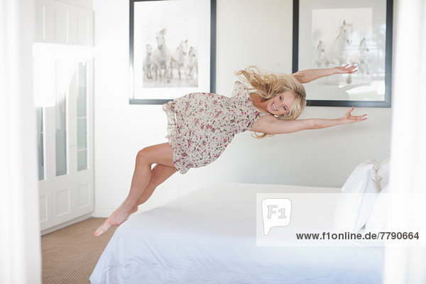 Young woman jumping on bed