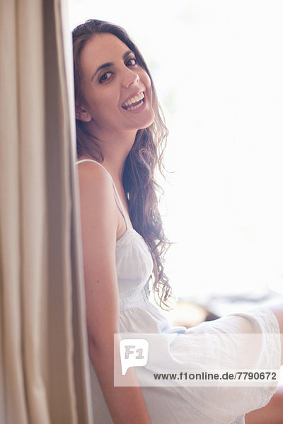 Young woman wearing sundress by window