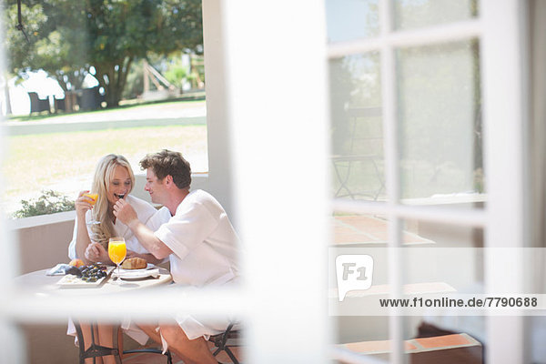 Young couple having breakfast on patio