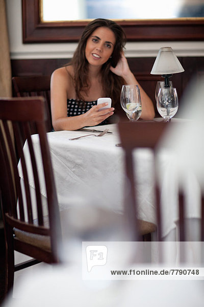 Young woman in restaurant using smartphone