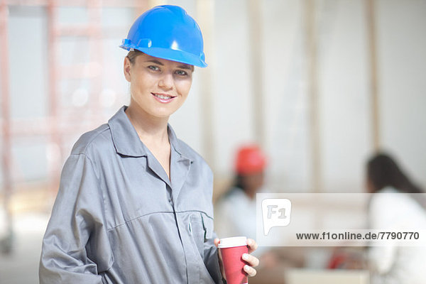 Lächelnde Bauarbeiterin mit Kaffee