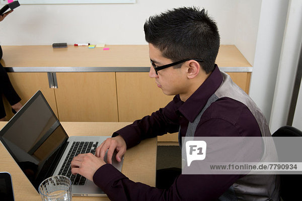 Young man wearing glasses using laptop