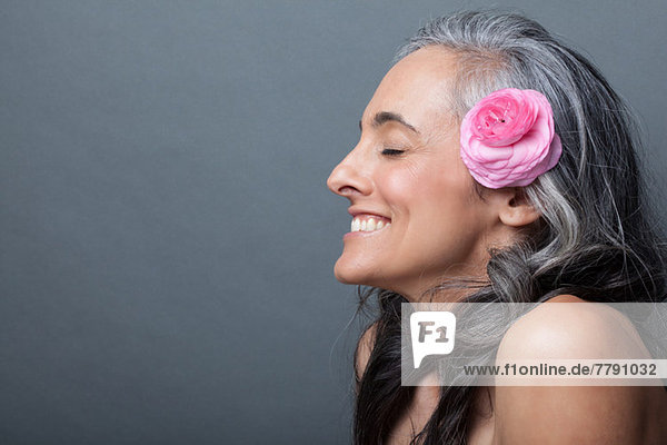 Reife Frau mit rosa Blume im Haar Augen geschlossen