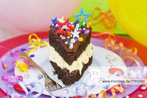 Ein Stück Schokoladenkuchen mit bunten Süssigkeiten für eine Party