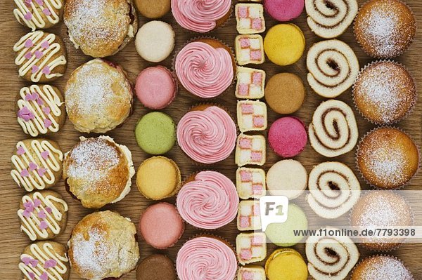 Reihen von Cupcakes  Scones  Macarons  Biskuitrolle und Stücke von Mini Battenburg Cake