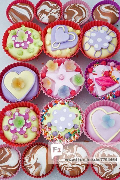 Viele Cupcakes in Plastikförmchen  mit Herzen  Lippen und Süßigkeiten dekoriert