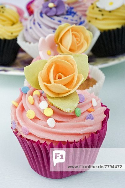 Mehrere Cupcakes mit Zuckerblumen und Zuckerkonfetti