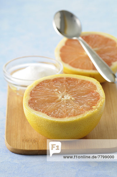 Close-up of Grapefruit cut in half with Bowl of Sugar and Spoon on Cutting Board  Studio Shot