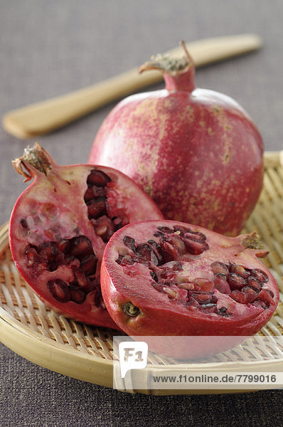 Close-up of Pomegranates on Tray  One cut in half on Grey Background  Studio Shot