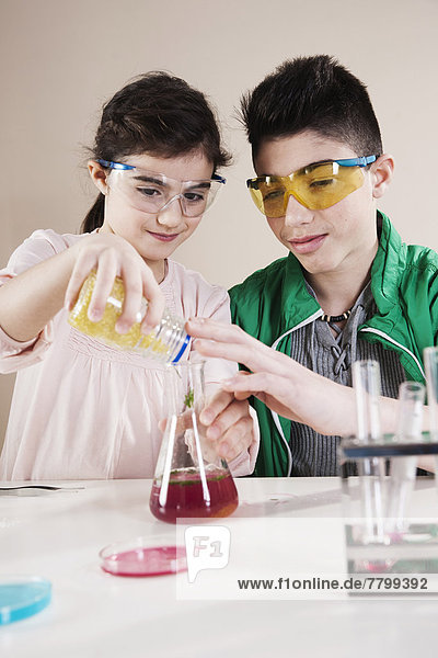 Boy and Girl wearing Safety Glasses Pouring substance into Beaker  Mannheim  Baden-Wurttemberg  Germany