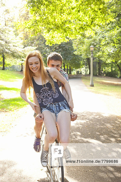Young couple riding bike together in a park on a warm summer day in Portland  Oregon  USA