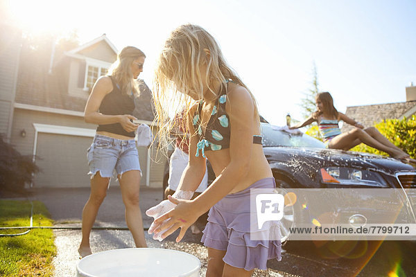 Family washing their car in the driveway of their home on a sunny summer afternoon in Portland  Oregon  USA