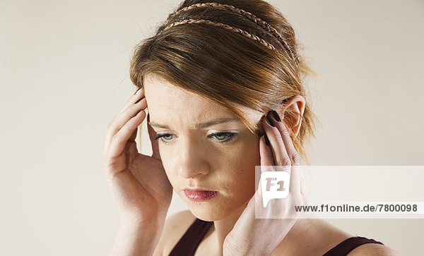 Head and shoulders portrait of teenage girl with hands on her head in studio.
