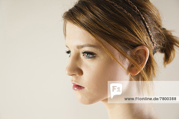 Close-up  Side View Portrait of Teenage Girl in Upsweep Hairstyle and wearing Make-up  Studio Shot on White Background