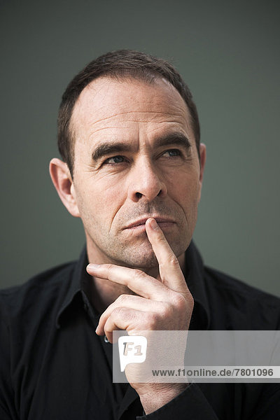 Head and Shoulders Portrait of Mature Man with Finger on Lips