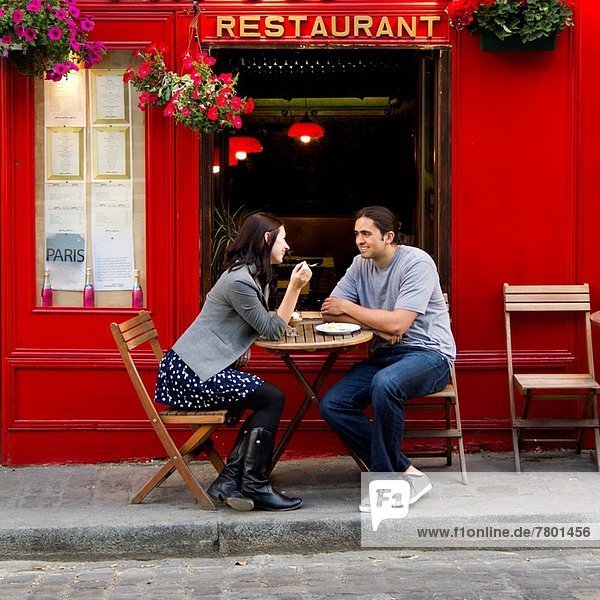 France Paris Young couple sitting in sidewalk cafe