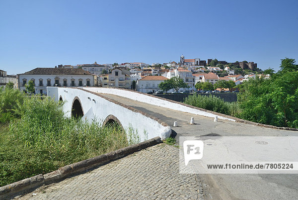 Old stone bridge crossing the Rio Arade river  in front of the historic town centre and the medieval castle of Castelo de Silves