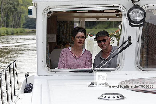 Frau und Mann am Steuer einer Penichette  Hausboot auf dem Canal des Vosges  früher Canal de l?Est
