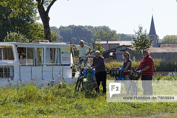 Holidaymakers in front of a house boat on the Canal des Vosges  formerly Canal de l'Est  after going shopping by bicycle