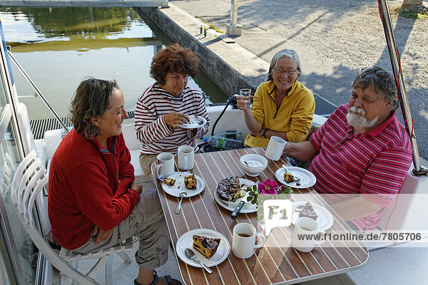 Urlauber trinken Kaffee auf der Heckterrasse einer Penichette Hausboot auf dem Canal des Vosges früher Canal de l?Est im Hafen