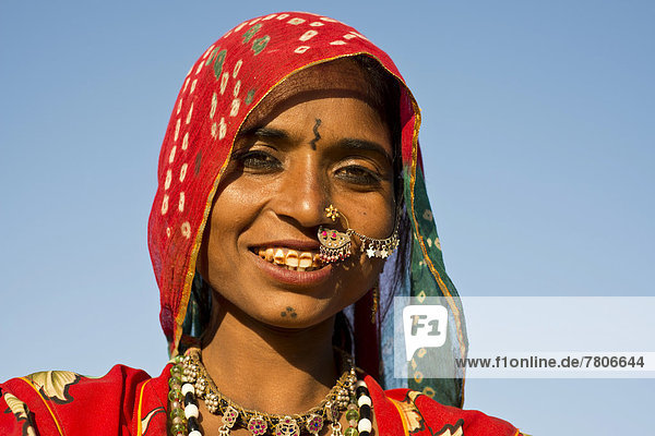 Lächelnde junge Inderin mit buntem Kopftuch und Schmuck  Porträt