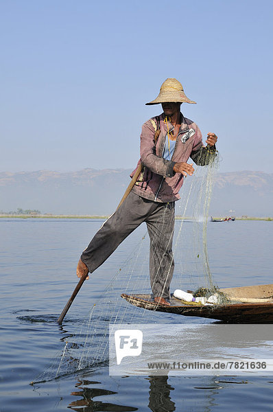 Einbeinruderer  Fischer mit Netz rudert stehend
