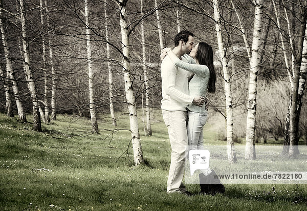 Young couple kissing in a birch forest