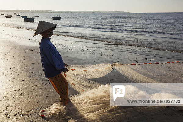 Fisch  Pisces  Frau  Strand  Küste  Sonnenaufgang  Morgendämmerung  Meer  ernst  angeln  Fischer  Fischernetz  Netz  Angler  Asien  Mui Ne  Vietnam  vietnamesisch
