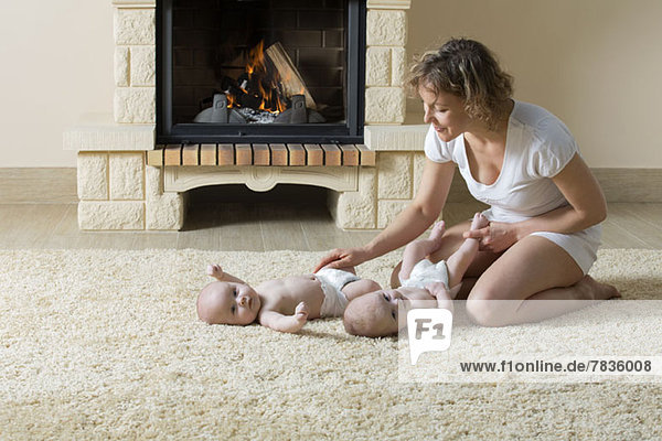 Mutter und Töchter auf Teppich vor dem Feuer