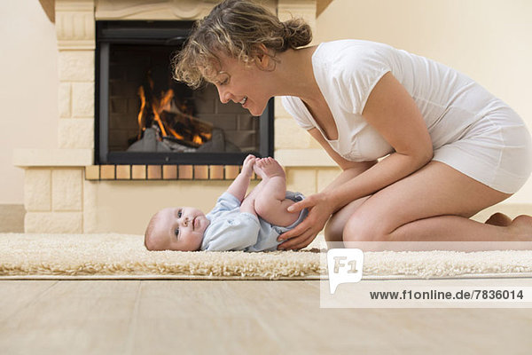 Mutter und Tochter auf Teppich vor dem Feuer