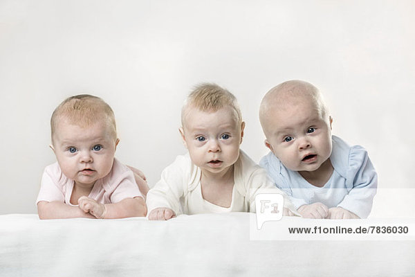Drei Babys machen lustige Gesichter