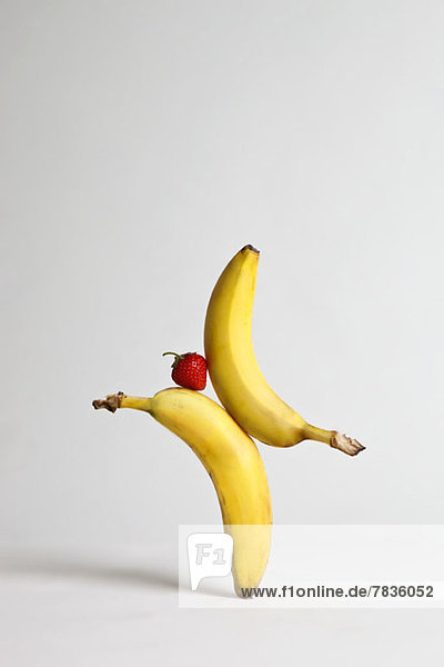 A strawberry balancing between two bananas