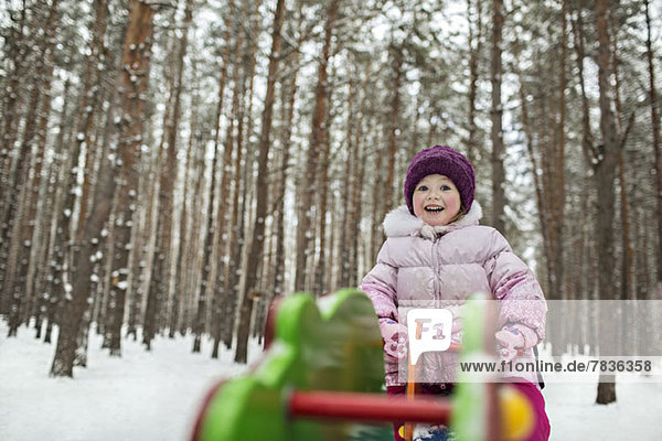 A young cheerful girl on a piece of playground equipment in winter